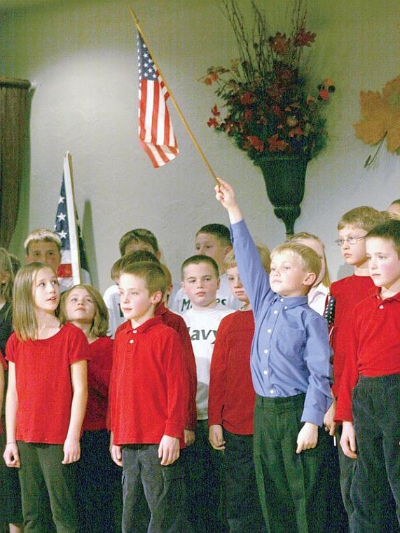 Canda Harbaugh/The Western News Chandler Bower holds up a flag during a Veterans Day program Friday night at Libby Christian Church, put on by Kootenai Valley Christian School.
