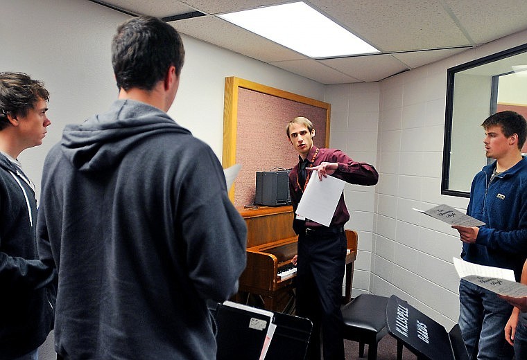 Peters plays a key on the piano to check the pitch of the choir's bass section during sectional rehearsal.