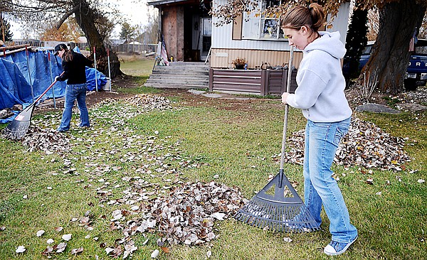 Mihkalie Britt, 13, right, and her cousin Brittany Emerson, 17, both of Columbia Falls, help rake up leaves outside their grandfather's home on Wednesday afternoon in Helena Flats.