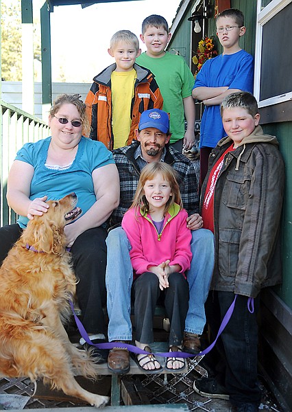 Earl and Jenny Rempel, their five children Jaydon, 7, clockwise from top left, Elijah, 10, Nick, 12, Russel, 13, and Denielle, 8, and their dog Sandy outside their home on Wednesday, in Evergreen.