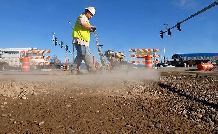 Tony SIlva cuts away the edges of asphalt on Northridge Drive as traffic moves along U.S. 93 in Kalispell on Monday afternoon. Northridge and Parkway drives have been closed to traffic in this area during a sewer-main improvement project.