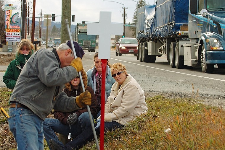 From left, Rita Leeseberg, Bryanne Hinsz, Tana Weller and Darla Weller watch as Bob Bigler of the American Legion Post 137 finishes installing a white cross for Marica Weller.