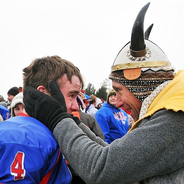 Michael Roessmann holds the face of Bigfork Vikings player Colter Mahlum as fans celebrate the team's win with the team on the field.