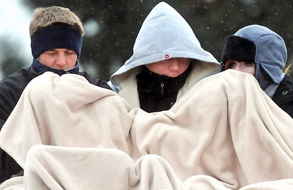 A trio of fans bundle together to attempt to stay warm.