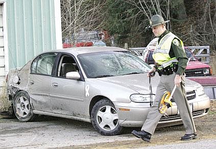 Montana Highway Patrol officer Joel Sieler works at the scene of an accident on Sunday afternoon on East Fifth Street Extension. The vehicle driven by Donovan Farnsworth hit a power pole, which snapped in half. Farnsworth was arrested on probation violation at the hospital.