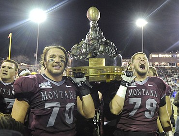 <p>Montana linemen Ben Weyer (70) and Max Kelly (79) hoist the Great Divide Trophy after beating the Bobcats 34-7. (Aaric Bryan/Daily Inter Lake)</p>
