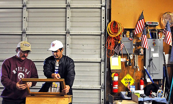 Chris gets some help as he works on fixing a portion of a cabinet at Hope Thrift.