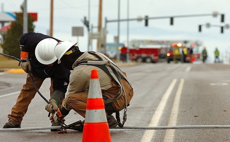 Flathead Electric Cooperative workers tend to a fallen power line Tuesday on West Reserve Drive. The transmission line came down when a clamp broke, causing a power outage that affected 10,000 electric customers. The clamp was repaired and power was restored to most customers by midafternoon.