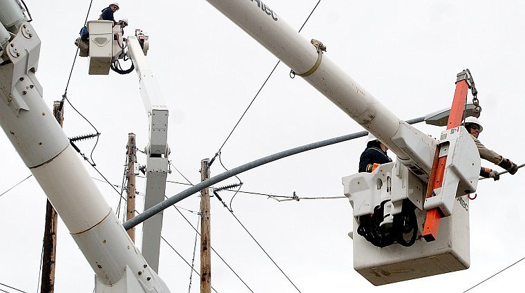 Flathead Electric Cooperative workers lift up a repaired power line near the intersection of West Reserve Drive and U.S. 93.