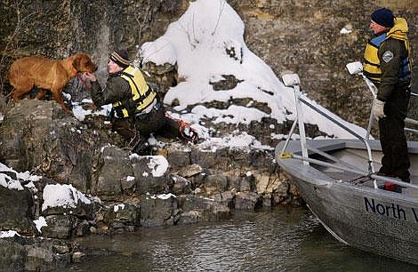 Jennifer Benware, left, with Flathead County Animal Control, calms an adult dog that was stranded on a cliff along the Flathead River near Hungry Horse Friday. &#147;I have never done a cliff rescue before. I was talking to it soft and approaching it slowly,&#148; Benware said. Animal Control officer Carl Talsma watches from the North Valley Search and Rescue boat captained by Brant Griffith. Craig Moore/Daily Inter Lake