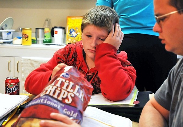 Robert eats some chips while getting some help with his homework.