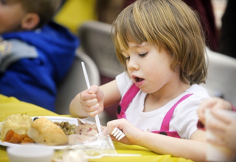 Brandee Reinsberg, 6, of Kalispell, takes the initiative with a knife while she is eating her Thanksgiving dinner with her family.