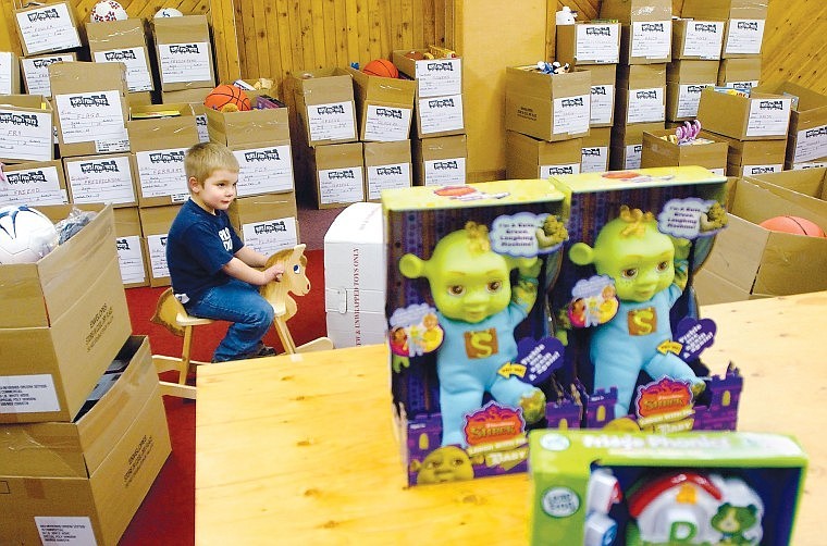 Rylin Peterson rides a wooden horse as he takes a break from helping his grandmother Cindy Rogers pack boxes at Toys for Tots. The program is taking donations before Dec. 17 at collection boxes throughout the valley.