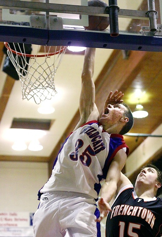 Columbia Falls' Kaleb Johnson (35) lays the ball up against the backboard next to Frenchtown's Jake Anderson Saturday evening.