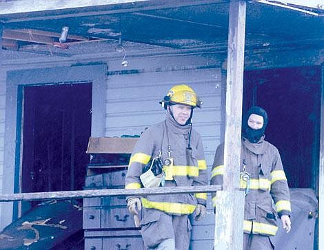 Zach Urness/Leader Staff - Firefighters Paul Bishop and Keith Paul survey the house after the blaze.