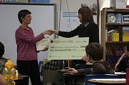 Kathee Hojem accepts a check from KPAX reporter Robin O'Day as part of the &quot;One Class at a Time&quot; award program.