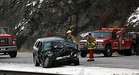 Rescue workers attempt to clear the three vehicles involved from Highway 200.