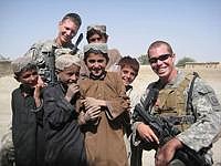 Kendall Seli (back) poses with a fellow Marine and several local children when in Afghanistan last year.