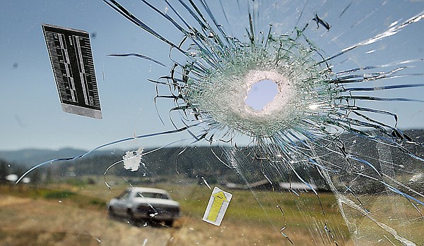 <p>This view looks through a bullet hole in the windshield of Deputy Roger Schiff’s vehicle in August 2011. In the background is the vehicle driven by Bryson Connolly.</p>