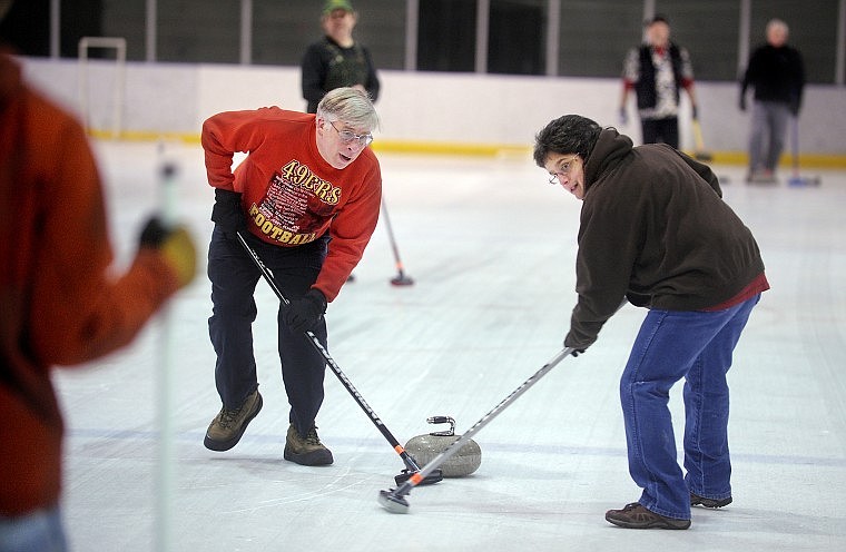 Dennis Dortch and Gina Kiehn, both of Kalispell, sweep the ice along the path they want the stone to follow.