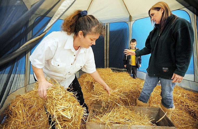 Cheryl Trumble, left, arranges hay for the manger scene in Bethlehem Village at the Boys and Girls Club of Glacier Country family night Christmas party held Tuesday evening. Dawn Griffin, at right, team leader for Spirit Club that hosts a weekly program for the boys and girls, was invited to present the Bethlehem scene for the family gathering. Austin Blain, 7, looks on in the background.