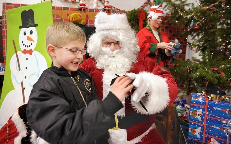 Aidan Matkovick, 6, of Kalispell, receives a toy spider from Santa Claus at the 20th anniversary Christmas at Our House hosted by the 495th Combat Sustainment Support Battalion of the National Guard. In the background is Pvt. Kimber Clark as one of Santa&#146;s elves.