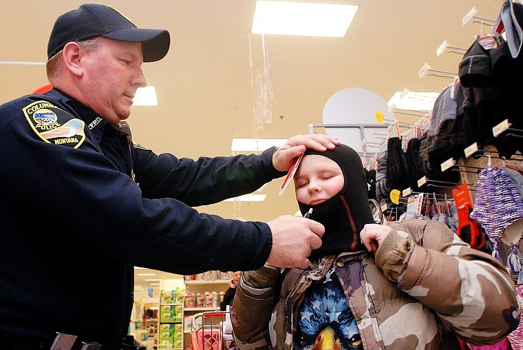 Columbia Falls Police Officer Todd Mertz helps fit a ski mask over Jayson Guring&#146;s head at Target during the department&#146;s annual Shop with a Cop Program on Thursday. Through donations taken over the course of the year, the police association was able to take five children shopping with a budget of $190 each.