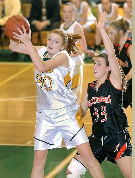 Whitefish post Tracy Schwada grabs a pass as Flathead's Leslie Quay defends during Thursday night's game in Whitefish. Flathead outpaced the Bulldogs, 7-41