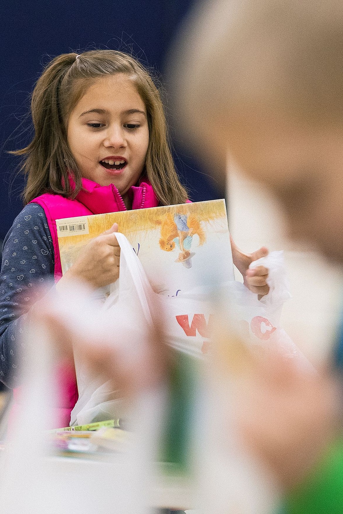 <p>Second-grader Olivia Maxwell chooses one of six books during the Jingle Books book fair.</p>