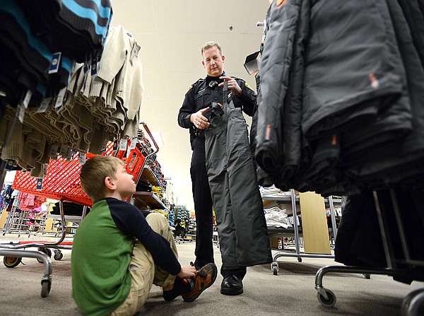 &lt;p&gt;Columbia Falls Police Officer Gary Stanberry holds up a pair of overalls for Isaiah Melvin, 7, on Wednesday at Target in Kalispell as part of the department&#146;s annual Shop with a Cop program.&lt;/p&gt;