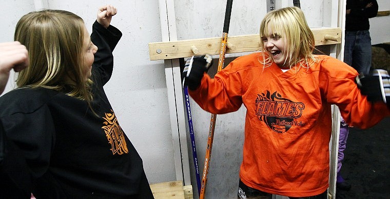 Shae Anderson, left, and friend Lauren Jochen flex their arms after getting suited up in the locker room.