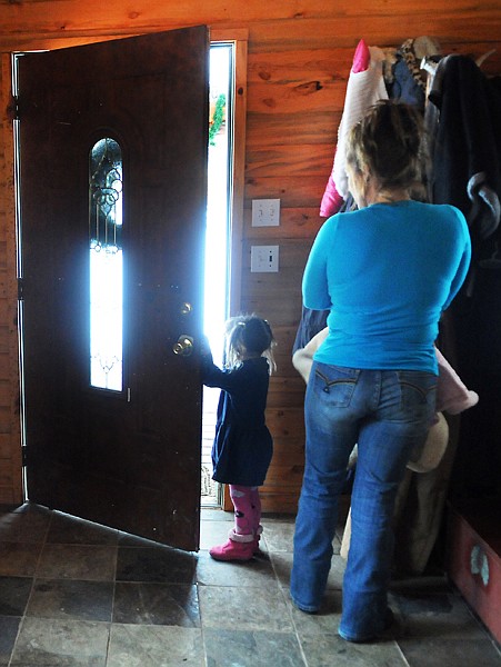 <p>Michele Vaugh-Wagar and her three-year-old daughter Eva peek out
the front door as they watch and wait for Jim and Colton Wagar to
arrive home from North Dakota on Friday morning in Kila.</p>