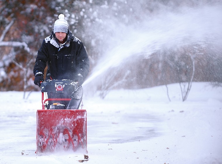 Adam Noble of Whitefish helps out a friend by clearing snow Monday morning from the parking lot of the Just Teezing Salon in Whitefish.