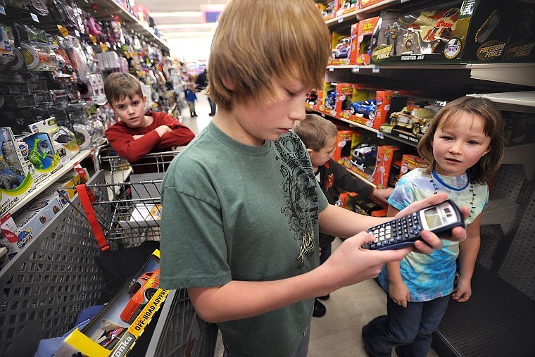 Shade Youso, a sixth-grader, Ahana Fox, right, a third-grader, and Kamron Rogers, left, a fourth-grader from Creston School, search for toys for a 4-year-old boy on Tuesday at Kmart.