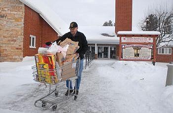 Salvation Army volunteer Pete Arneson delivers a shopping basket full of Christmas donations for a family at the church on Thursday. Christmas donations are down 20 percent while demand is up 40 percent compared to this time last year, according to Salvation Army Maj. Merry Svenson. Garrett Cheen/Daily Inter Lake