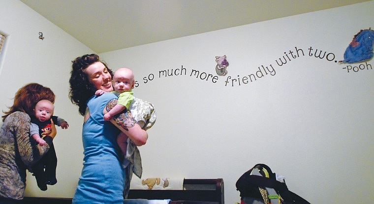 Britney Wheeler and her mother Erin Gilbert lift Davin, left, and Easton out of their crib before feeding them.