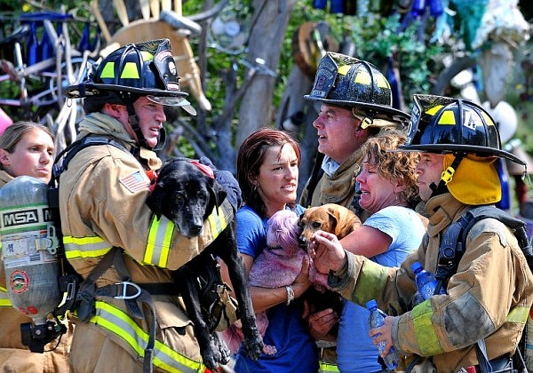 Kalispell Firefighter Brian Rauch, left, holds up a rescued dog while Traci Stolte and Debbie Huntingon (light blue) hold two other dogs standing next to Whitefish firefighters Mitch Avelar and Matt Weller after fire crews helped to rescue dogs from Stolte's home and business &quot;Stolte's Pet Shop on Highway 93 south of Whitefish Wednesday afternoon. All fifteen dogs and two cats made it out safely.