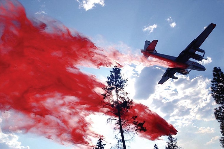 An air tanker drops a load of fire retardant at treetop level on a wildfire in a rural residential area near Kalispell in summer 2001. Many homes in the area were saved by the drops of fire retardant.