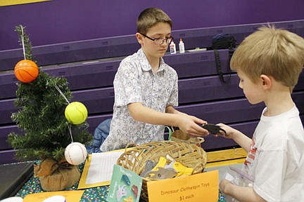 &lt;p&gt;Second grader Tristan buys a dinosaur clothespin from Owen during Linderman Elementary's All-School Christmas Market on Thursday, Dec. 18. Vince Lovato / Leader photo&lt;/p&gt;