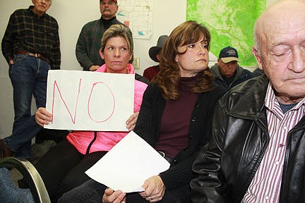 <p>Natalie Champoux, of Mission, holds up a sign protesting the Water Compact recently agreed upon by the CSKT and the state. She was one of more than 50 irrigators who packed the Mission Valley Irrigation District Tuesday for the Flathead Joint Board of Control's special meeting.</p>
