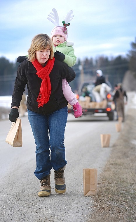 Kim Lister and her granddaughter Emilee Lister, age 3, walk along Rose Crossing doing &quot;quality control&quot; on Thursday as they and other volunteers work to line the street with 1500 lights in celebration on Christmas Eve. The residents of Rose Crossing have been placing luminarias for more than 20 years. Lister said quality control is one of the most vital aspects of making the luminarias last. The bags must have a good amount of sand at their base, the sand must be spread out to the corners to keep the bag open so the candle can get enough air, and the candles need to be cenered with their wicks straight up. If all goes well volunteers have found candles still burning Christmas morning when the luminarias are collected Christmas morning.