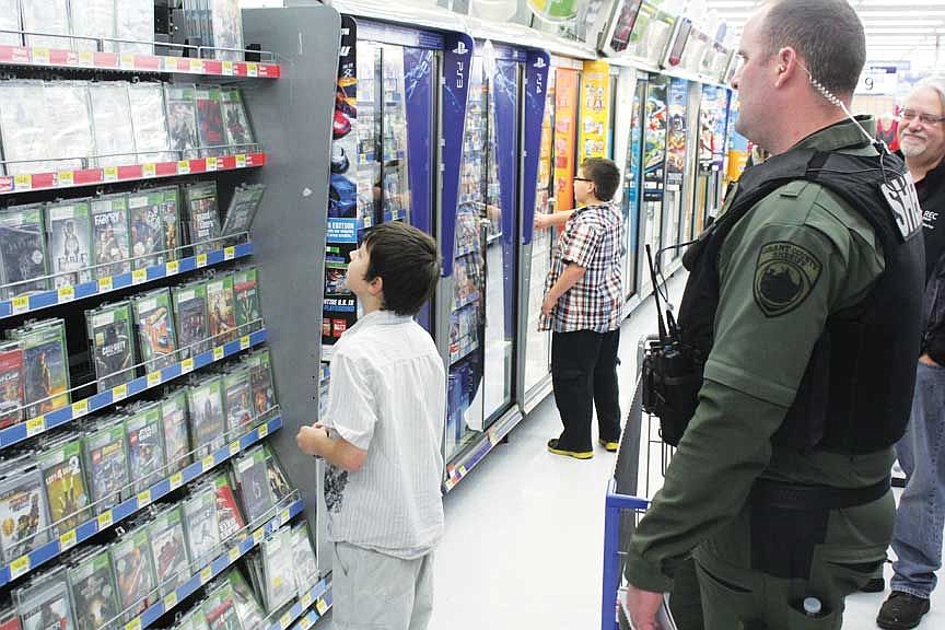 Deputy Jaret Fulbright and 11-year-old Andrew Curtis discuss which video game Andrew should buy.