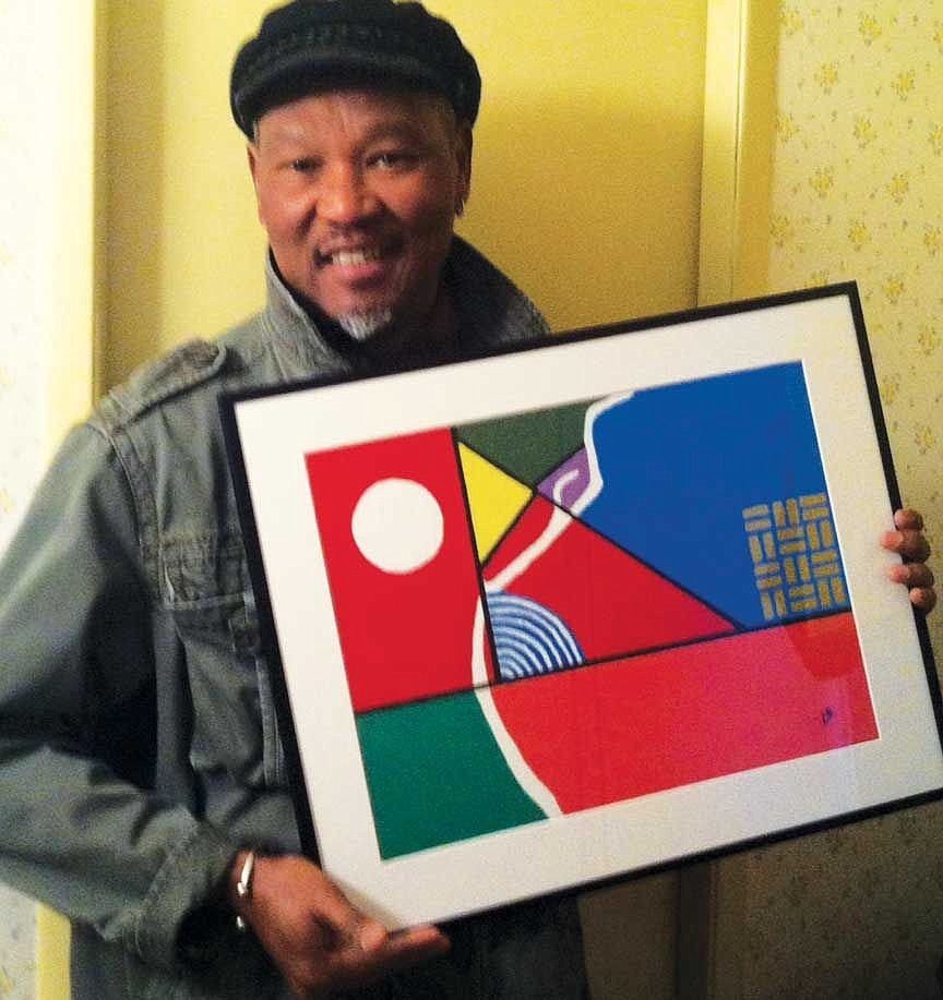 Quincy artist Cheikh Diouf holds one of his paintings. His first collection is now on display at the Quincy Public Library.