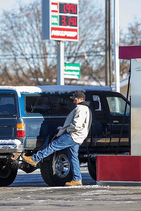 &lt;p&gt;Marty Garitone, of Mullan, Idaho, kicks snow off his truck while he waits for his tank to fill at the Cenex on Government Way in Dalton Gardens. Gas prices fell to $1.99 per gallon for regular fuel.&lt;/p&gt;