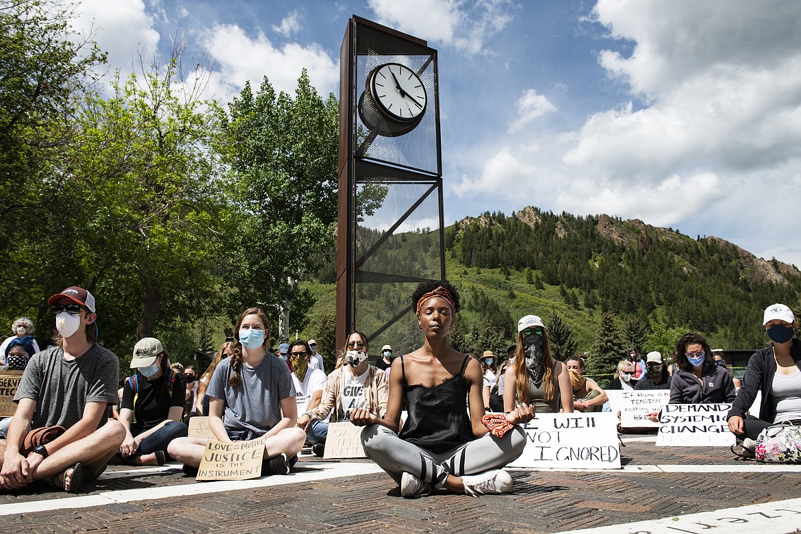 Jenelle Figgins, center, leads a moment of silent meditation before protesters march through the streets of Aspen, Colo., Sunday, May 31, 2020, to demonstrate against the death of George Floyd. Protests were held throughout the country over the death of Floyd, a black man who died after being restrained by Minneapolis police officers on May 25.  (Kelsey Brunner/The Aspen Times via AP)