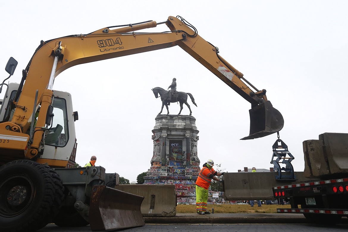 Workers for The Virginia Department of General Services install concrete barriers around the statue of Confederate General Robert E. Lee on Monument Avenue Wednesday, June 17, 2020, in Richmond, Va. The barriers are intended to protect the safety of demonstrators as well as the structure itself. (AP Photo/Steve Helber)