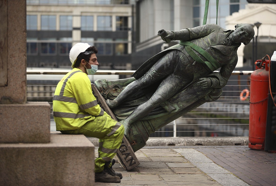 A worker rests after the statue of slave owner Robert Milligan was taken down, at West India Quay, east London, Tuesday, June 9, 2020, after a protest saw anti-racism campaigners tear down a statue of a slave trader in Bristol. London's mayor says statues of imperialist figures could be removed from the city's streets, in the latest sign of change sparked by the death of George Floyd. London Mayor Sadiq Khan says he is setting up a commission to ensure monuments reflect the city's diversity. (Yui Mok/PA via AP)