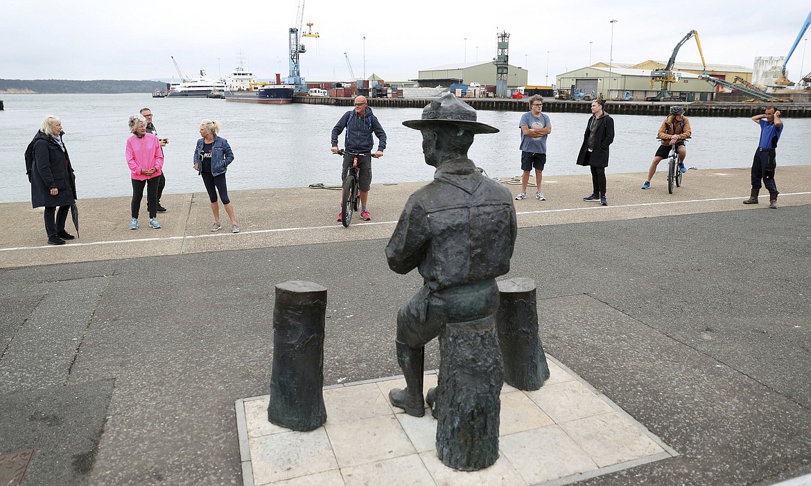 People look at the statue of the founder of the Scout movement Robert Baden-Powell on Poole Quay in Dorset, England ahead of its expected removal to "safe storage" following pressure to remove it over concerns about his alleged actions while in the military and "Nazi sympathies" Thursday June 11, 2020. (Andrew Matthews/PA via AP)