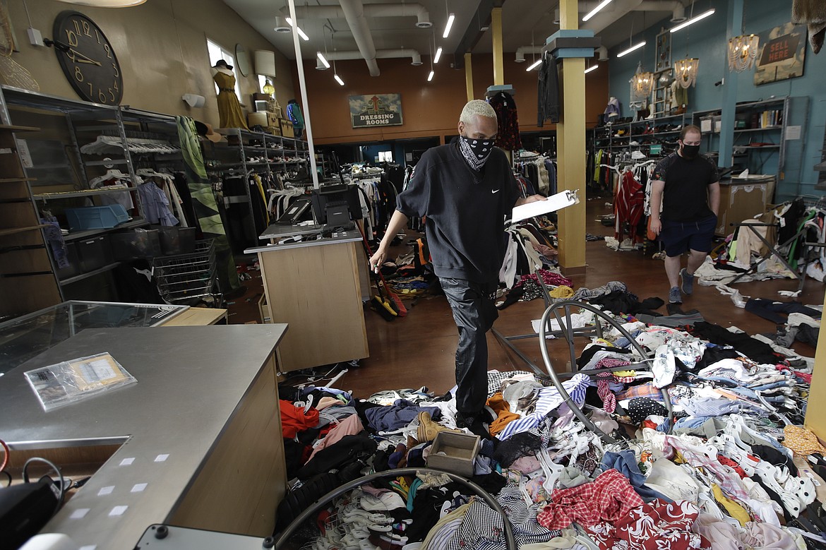 Terrel Ransom, center, store manager for Buffalo Exchange walks over clothes in the damaged store, Sunday, May 31, 2020, in Los Angeles, following a night of unrest and protests over the death of George Floyd, a black man who was in police custody in Minneapolis. Floyd died after being restrained by Minneapolis police officers on May 25.   (AP Photo/Marcio Jose Sanchez)