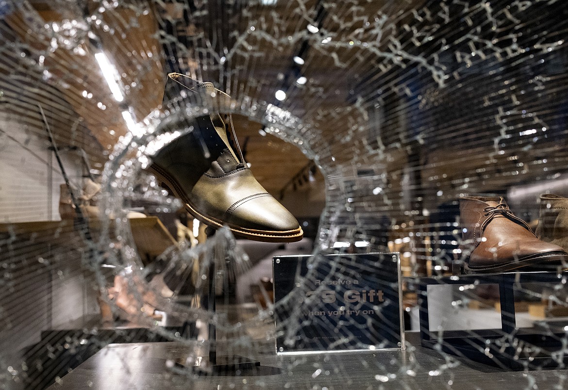 In this Monday, June 1, 2020, photo, shoes are seen through a hole in the damaged glass in the Chelsea neighborhood of Manhattan, a borough of New York after continued protests against the death of George Floyd, who died in Minneapolis police custody on May 25. (AP Photo/Craig Ruttle)